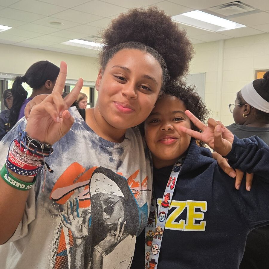 2 participants smile with peace signs during in-school program