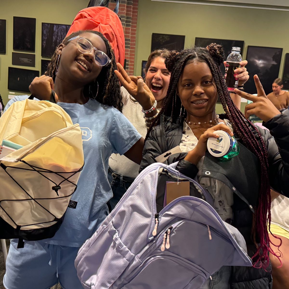 two participants holding new back-to-school backpacks with mentor