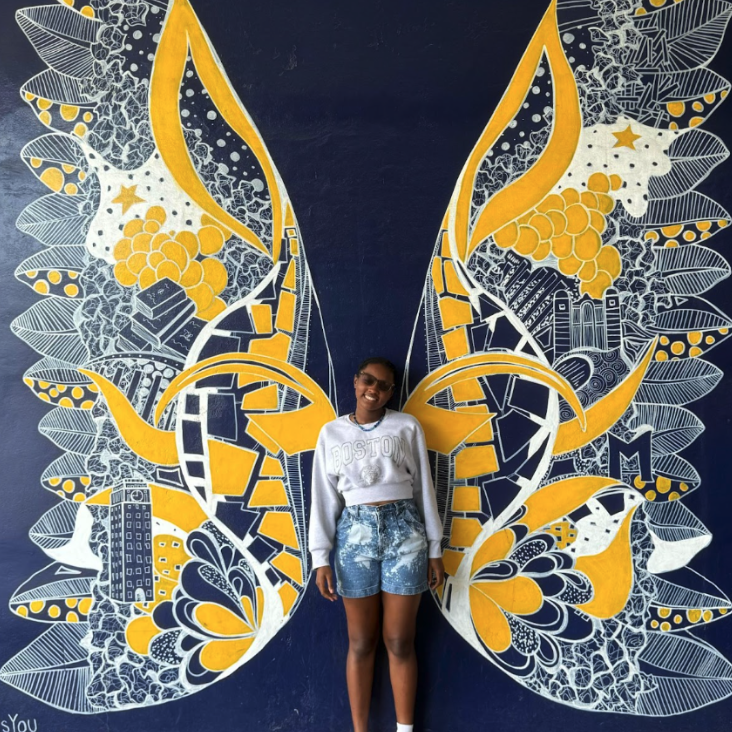 Participant standing in front of mural with wings